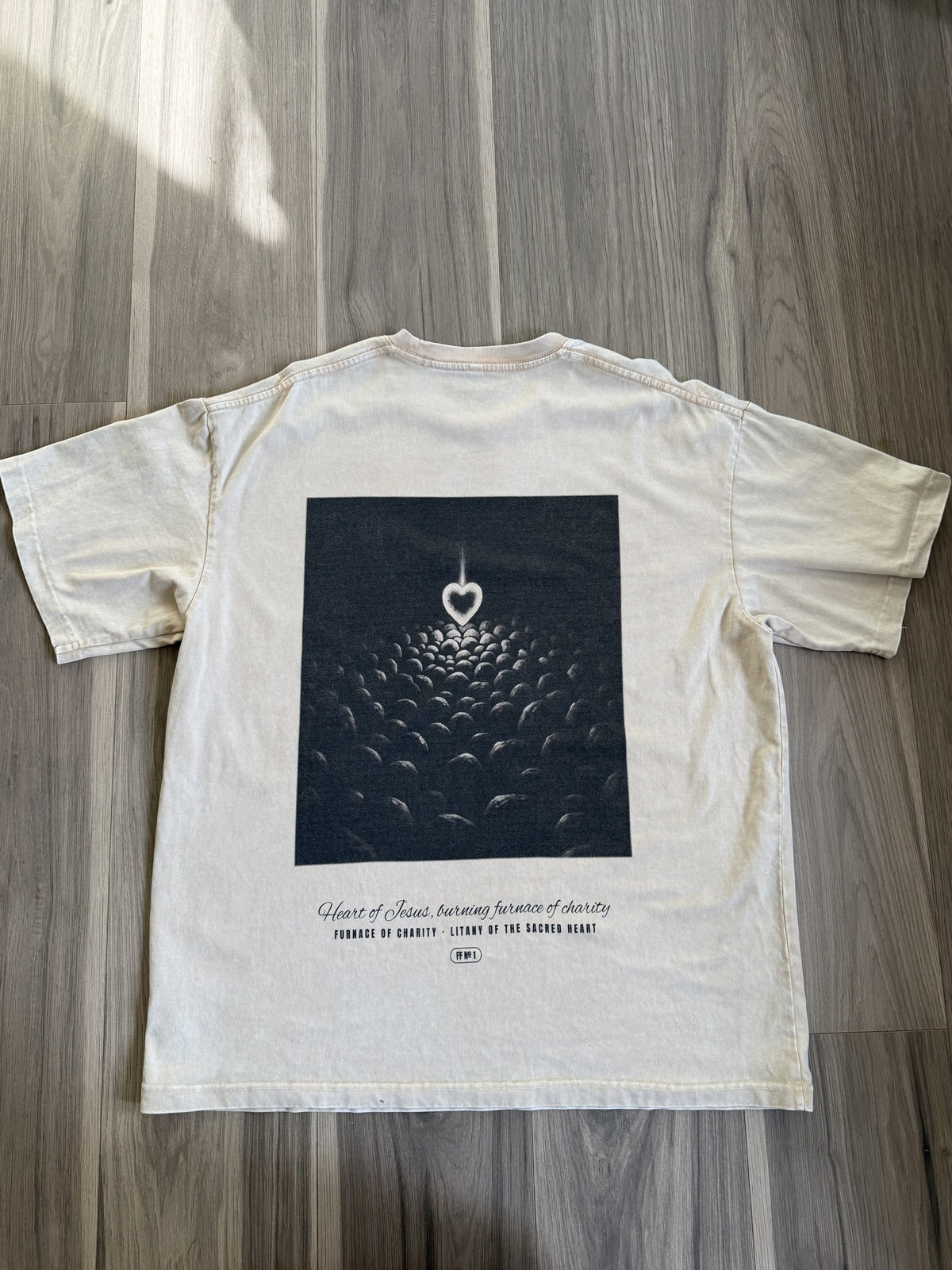 Furnace of Charity back print, apricot tee, flat lay